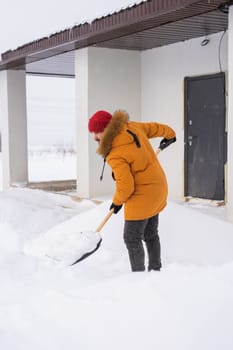 Man removing snow and ice from the sidewalk in front of house. Winter season.