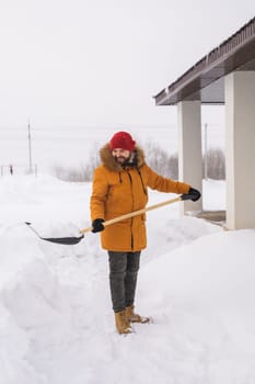 A man cleans and clears the snow in front of the house on frosty day. Cleaning the street from snow on a winter day. Snowfall and severe snowstorm in winter