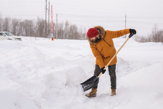 A man cleans and clears the snow in front of the house on frosty day. Cleaning the street from snow on a winter day. Snowfall and severe snowstorm in winter