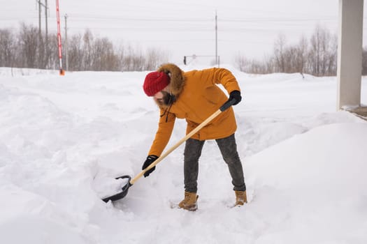 Man removing snow and ice from the sidewalk in front of house. Winter season.