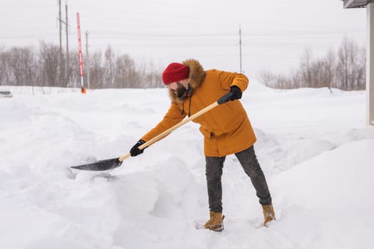 Man cleaning snow from sidewalk and using snow shovel. Winter season.