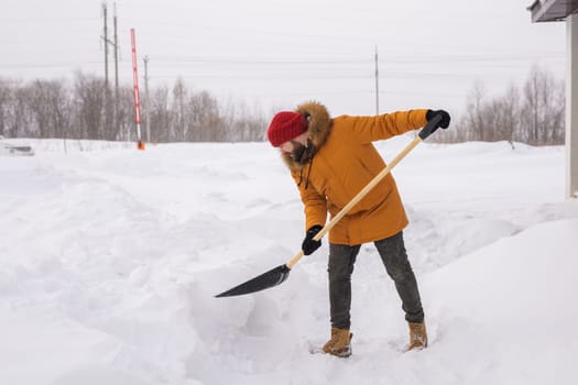 Man removing snow and ice from the sidewalk in front of house. Winter season.