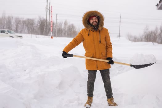 A man cleans and clears the snow in front of the house on frosty day. Cleaning the street from snow on a winter day. Snowfall and severe snowstorm in winter