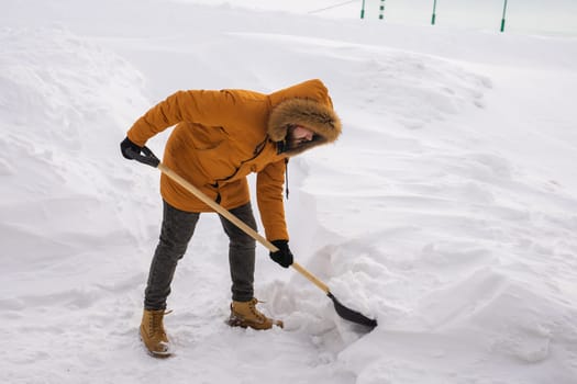 A man cleans and clears the snow in front of the house on frosty day. Cleaning the street from snow on a winter day. Snowfall and severe snowstorm in winter