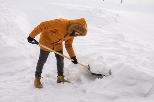 Man is clearing the snow near house and on staircases hovelling at the winter season. Winter storm and season specific.