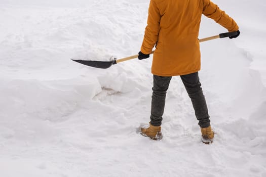 Man cleaning snow from sidewalk and using snow shovel. Winter season.