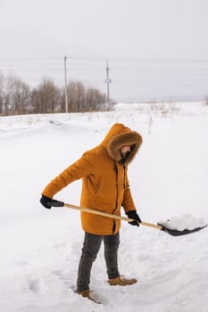 A man cleans and clears the snow in front of the house on frosty day. Cleaning the street from snow on a winter day. Snowfall and severe snowstorm in winter