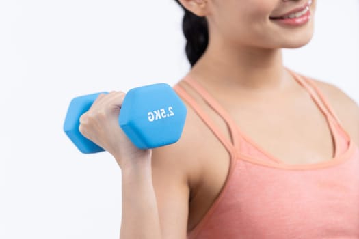 Vigorous energetic woman doing dumbbell weight lifting exercise on isolated background. Young athletic asian woman strength and endurance training session as body workout routine.