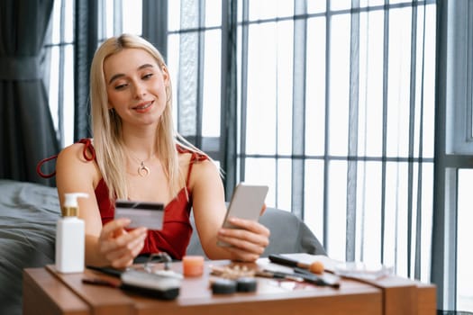 Young woman using online payment app and digital wallet on smartphone to pay with credit card. E commerce shopping and modern purchasing via mobile internet. Blithe