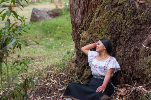 copy space of indigenous woman sitting resting in an ancient tree with moss. The girl smiling with a face of peace and harmony. Earth day. High quality photo