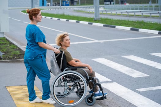 Red-haired nurse pushing an elderly woman in a wheelchair across the road