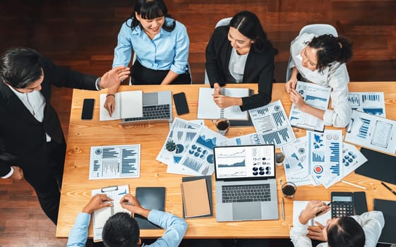 Wide top view of diverse group of business analyst team analyzing financial data report paper on meeting table. Chart and graph dashboard by business intelligence analysis. Meticulous