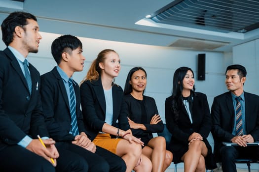 Young Asian and Caucasian audience sitting and listen to speaker in group meeting presentation at office. Businessmen and businesswomen in training workshop. International multicultural business. uds