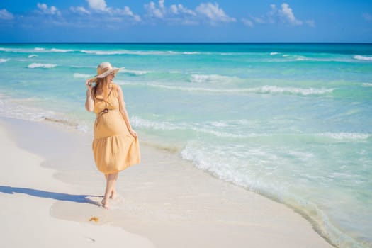 Radiant and expecting, a pregnant woman stands on a pristine snow-white tropical beach, celebrating the miracle of life against a backdrop of natural beauty.