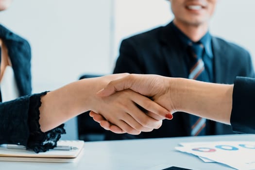 Business people agreement concept. Businessman and Asian businesswoman do handshake in the office. uds