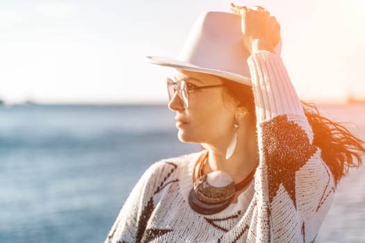 Portrait of a curly haired woman in a white hat and glasses on the background of the sea