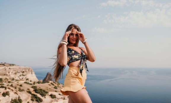 Woman travel sea. Happy tourist taking picture outdoors for memories. Woman traveler looks at the edge of the cliff on the sea bay of mountains, sharing travel adventure journey.