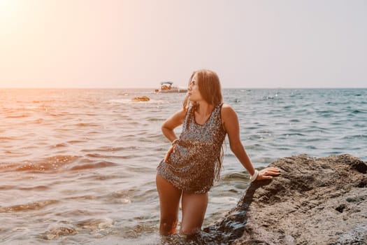 Woman travel sea. Young Happy woman in a long red dress posing on a beach near the sea on background of volcanic rocks, like in Iceland, sharing travel adventure journey