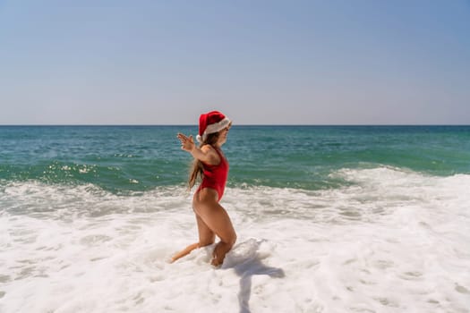 A woman in Santa hat on the seashore, dressed in a red swimsuit. New Year's celebration in a hot country