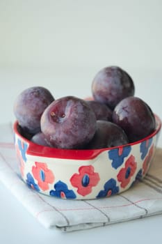 Fresh plums in a bowl on table ,