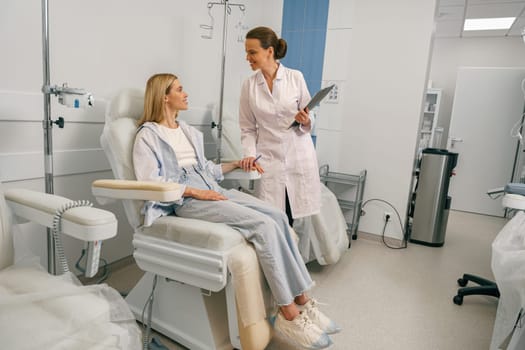 Doctor talking with patient while preparing her for infusion drip in hospital . High quality photo