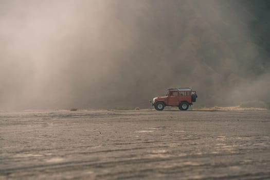 Offroad red jeep at misty Bromo mountain. Landscape view in fog of travelling offroad SUV vehicle in Semeru national park