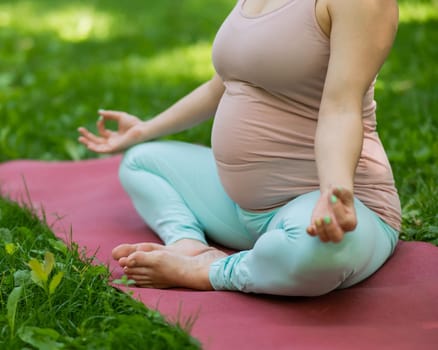 Prenatal yoga. Caucasian pregnant woman doing butterfly pose in the park