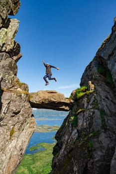 Happy man is jumping on the top of the mountain. He rejoices at the success of victory over himself, overcoming himself. Hiker on top of Djevelporten, Norway. rock stack in mountain Lofoten Island