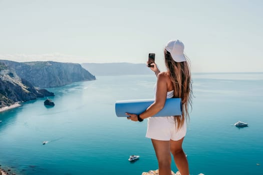 Young woman with black hair, fitness instructor in pink sports leggings and tops, doing pilates on yoga mat with magic pilates ring by the sea on the beach. Female fitness daily yoga concept