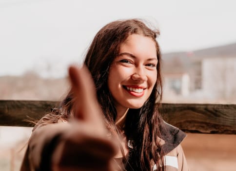 Happy young smiling woman with freckles outdoors portrait. Soft sunny colors. Outdoor close-up portrait of a young brunette woman and looking to the camera, posing against nature background.