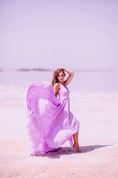 Woman pink salt lake. Against the backdrop of a pink salt lake, a woman in a long pink dress takes a leisurely stroll along the white, salty shore, capturing a wanderlust moment