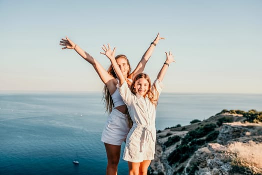 Close up portrait of mom and her teenage daughter hugging and smiling together over sunset sea view. Beautiful woman relaxing with her child.