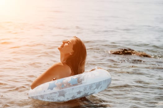 Woman summer sea. Happy woman swimming with inflatable donut on the beach in summer sunny day, surrounded by volcanic mountains. Summer vacation concept