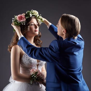 Concept of lesbian wedding. Groom puts wreath on bride's head