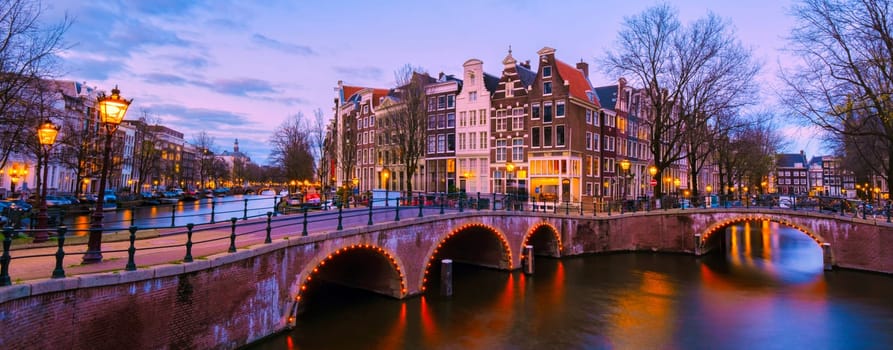 Amsterdam Canal in the evening during sunset, Amsterdam Canal bridge with old historical houses at night in the Netherlands. Panoramic view at the historical old town of Amsterdam