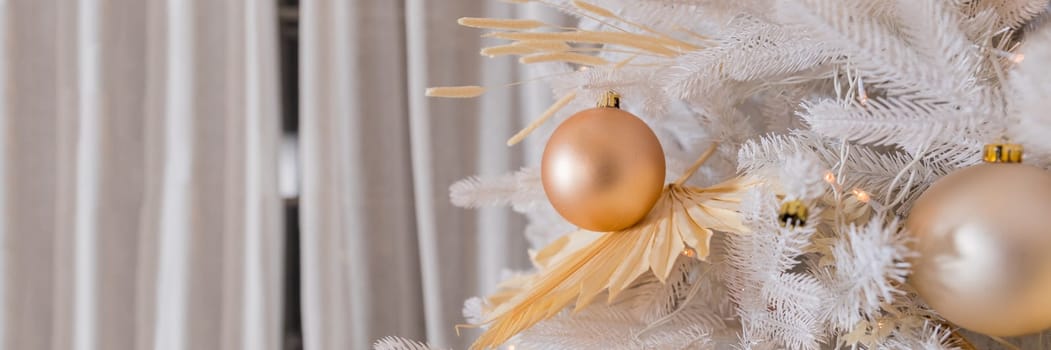 Close up of beautiful fir branches with shiny golden, silver and white baubles or balls, xmas ornaments and garland lights
