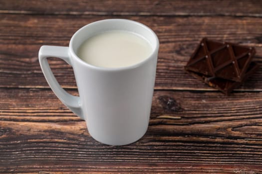 Milk with chocolate in black cup on wooden table