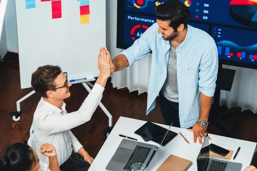 Analyst team leader celebrate and high five together with his colleague after successful data analysis meeting using FIntech software power with business intelligence or BI dashboard. Prudent