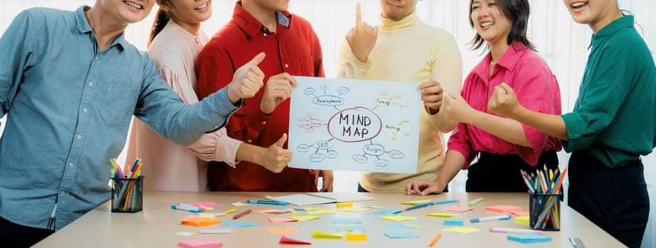 A cropped image of successful businesspeople presents new product marketing strategy using a mind map. Young creative business team brainstorm marketing idea together at modern office. Variegated.
