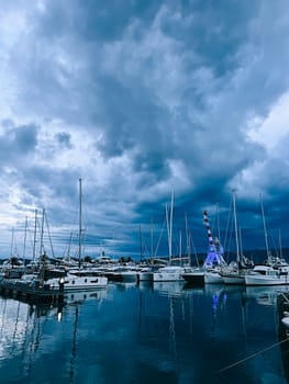 Marina with sailing yachts and port crane against the twilight sky. High quality photo
