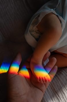 A man holds his newborn son by the leg. Beam of light through a prism