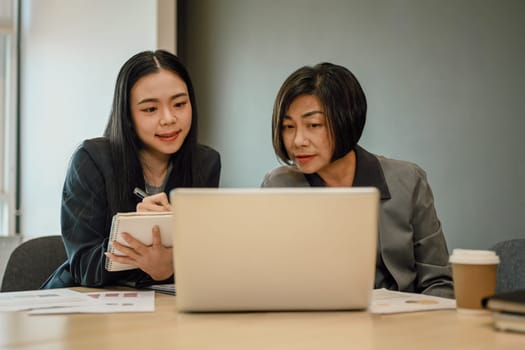 Businesspeople looking at laptop screen working together for important project in office.