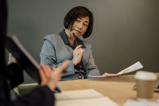 Senior female manager listening to colleagues project ideas during corporate briefing.