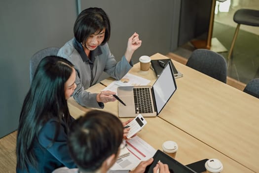 Above view of senior businesswoman in formal suit explaining strategy to her colleagues during meeting.