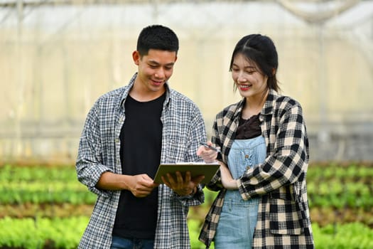 Young farmers using digital tablet for checking and controlling systems in greenhouse.