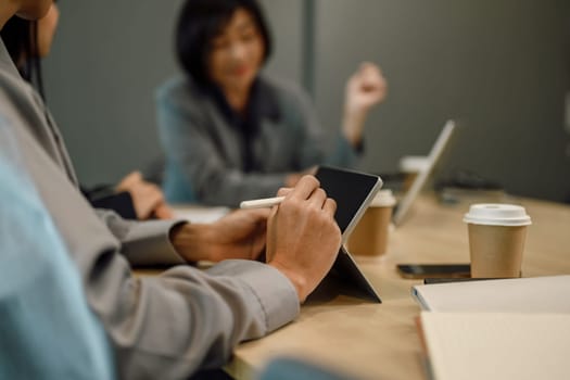 Cropped shot of businesswoman writing notes on digital tablet at boardroom table.