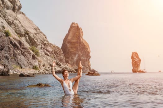 Young woman with black hair, fitness instructor in pink sports leggings and tops, doing pilates on yoga mat with magic pilates ring by the sea on the beach. Female fitness daily yoga concept