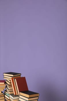 Stack of books on a purple background in the library Education