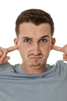 Young annoyed caucasian man in t-shirt covers ears with hands fingers on white background