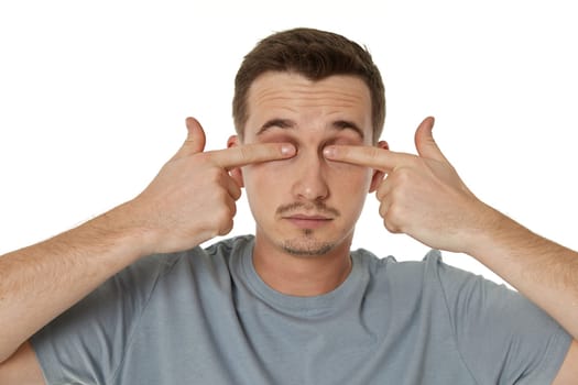 man covering eyes with hands on white background
